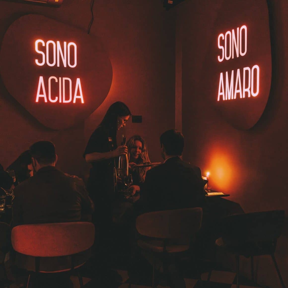 Cuplu ia masa la restaurant Grande Bellezza din București, cu lumina difuză, roșiatică