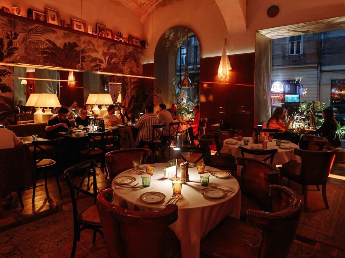 mai multi oameni iau cina in cadrul intim, cu lumina difuza, de la Restaurant Artegianale Brasov