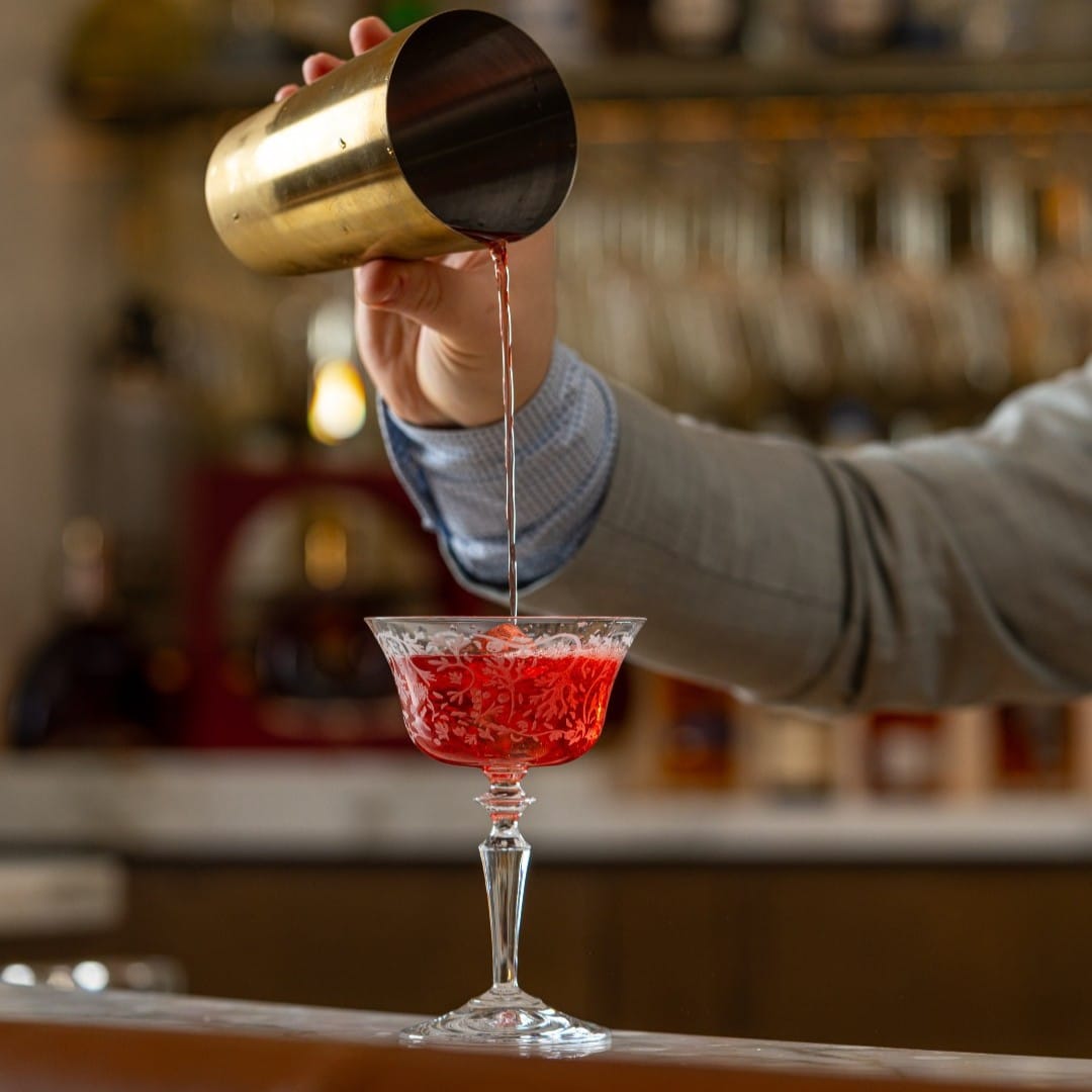 Barman toarnă bautura in pahar la Heritage Bar din București.