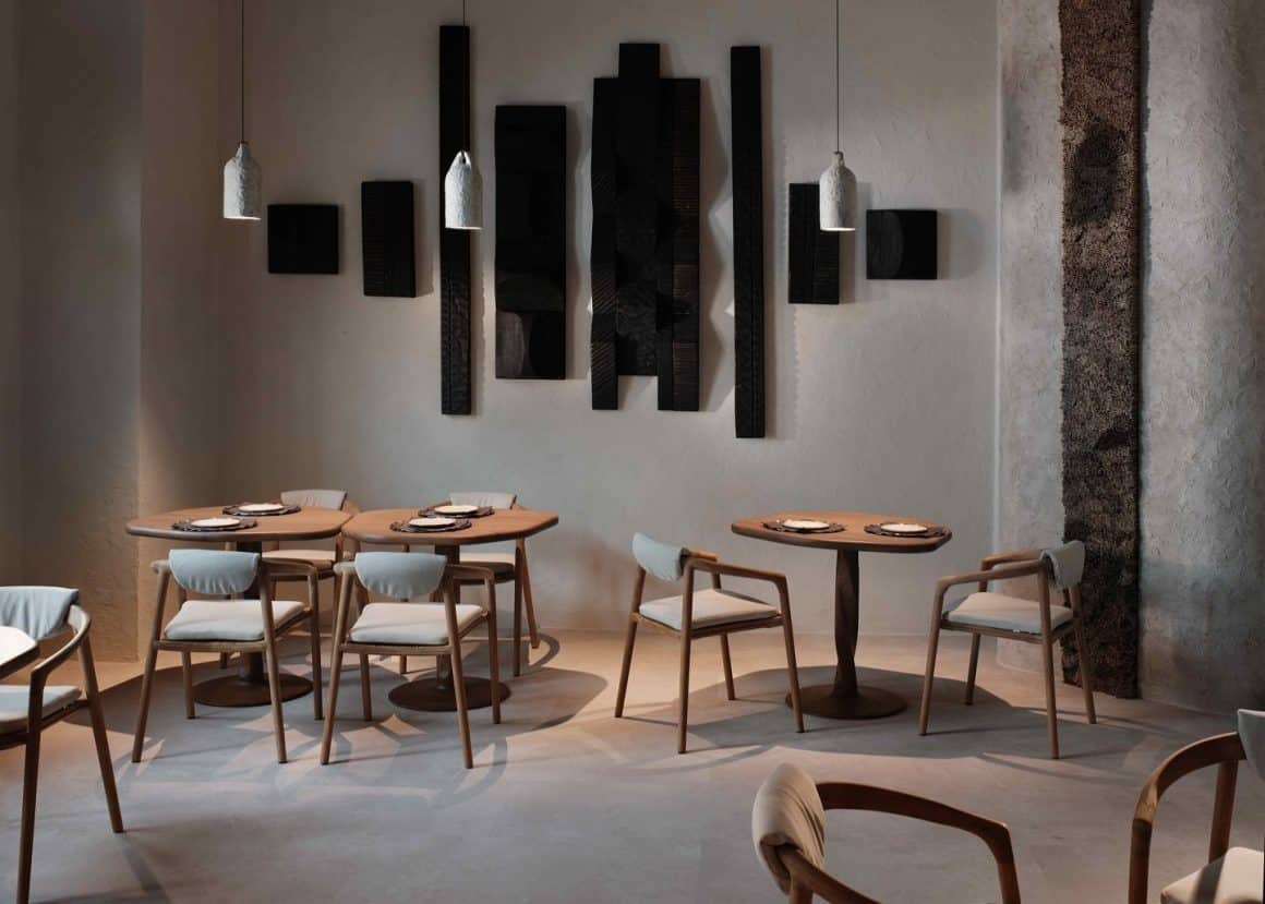 Sală de restaurant éto București, cu mese rotunde din lemn, scaune elegante și instalație artistică din panouri negre pe perete, decor minimalist pentru o experiență de fine dining