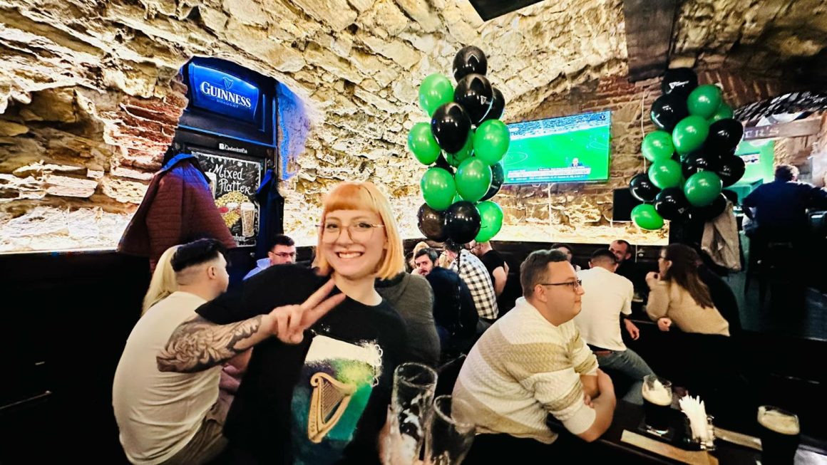 Imagine din interiorul barului O’Peter’s, pub irlandez din Cluj, decorat cu baloane verzi si negre de St Patrick Day, cu oameni care stau la mese si beau bere Guinness