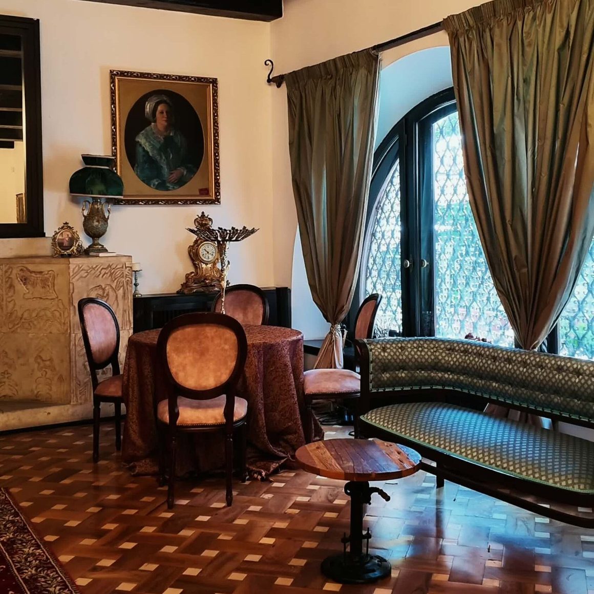 Salon din interiorul vilei, cu parchet, draperii și portret de epocă, la Art Deco Café