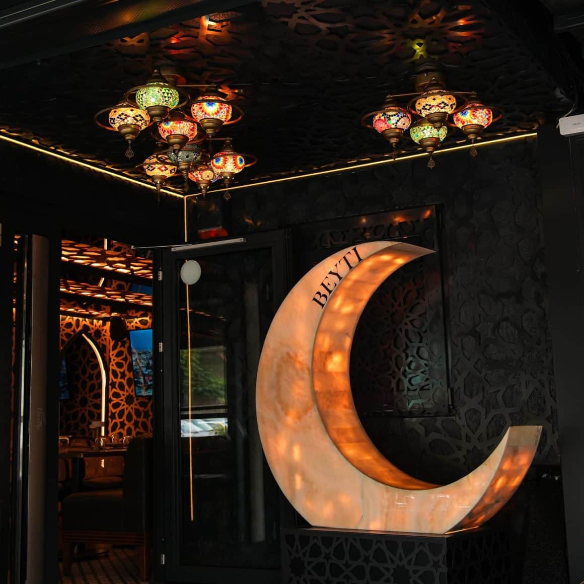 Detaliu de decor cu o luna luminoasa atarnata de perete si lampi arabe de tavan la Beyti restaurant turcesc București