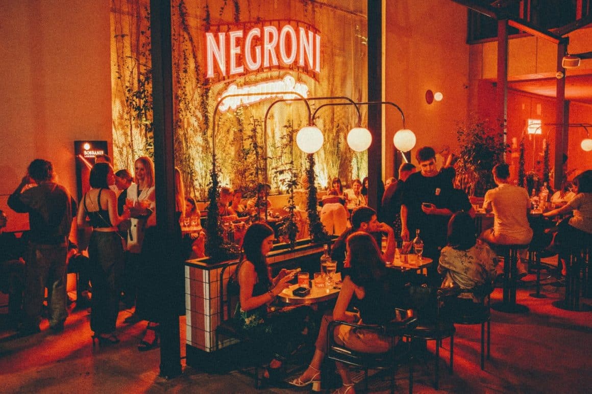 Mai multi oameni seata pe terasa la Negroni Aperitivo Bar, stau de vorba si se relaxeaza la un pahar de aperitivo în București