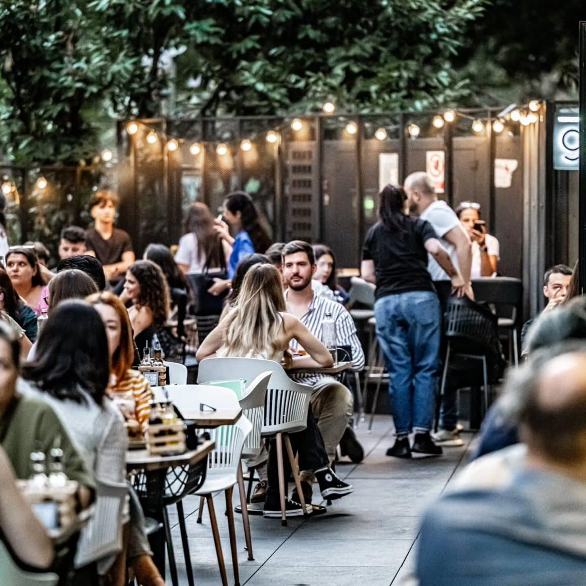 Mai multi oameni seara pe terasa la Ever After, stau de vorba si se relaxeaza la un pahar de aperitivo în București