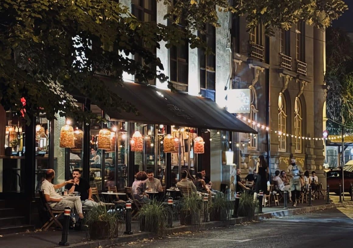 Mai multi oameni seara pe terasa stradala de la Salon Golescu, stau de vorba si se relaxeaza la un pahar de aperitivo în București