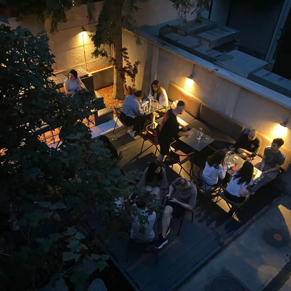 Mai multi oameni seara pe terasa la Teoria Cocktail Bar, stau de vorba si se relaxeaza la un pahar de aperitivo în București