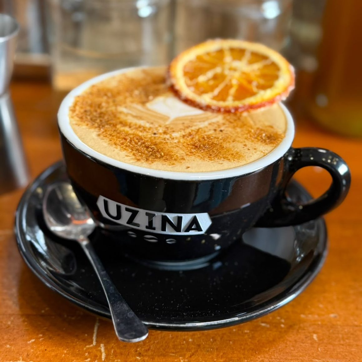 Orange Cinnamon Latte de la Uzina Coffee, București, cu spumă de lapte, scorțișoară și felie de portocală deshidratată.