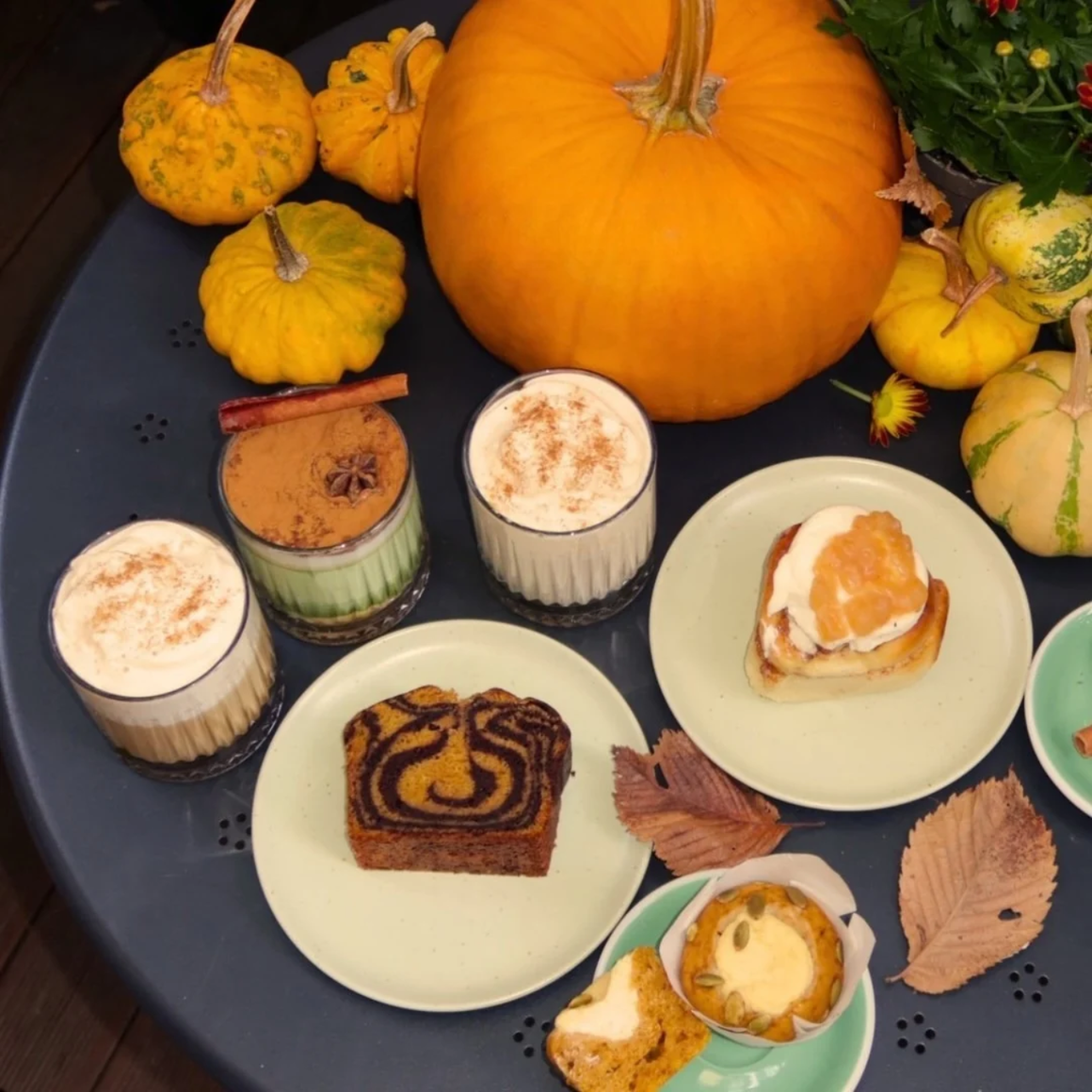Latte-uri București la AM.PM, cu Pumpkin Spice Latte, Apple Latte și Cardamom Latte, servite alături de deserturi și decorate cu dovleci de sezon.