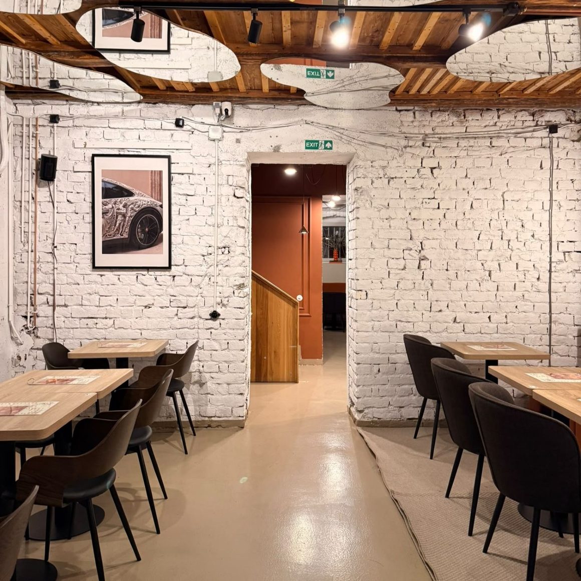 Interiorul Cremma Café din București, cu pereți din cărămidă albă, mese din lemn și mobilier în stil industrial.