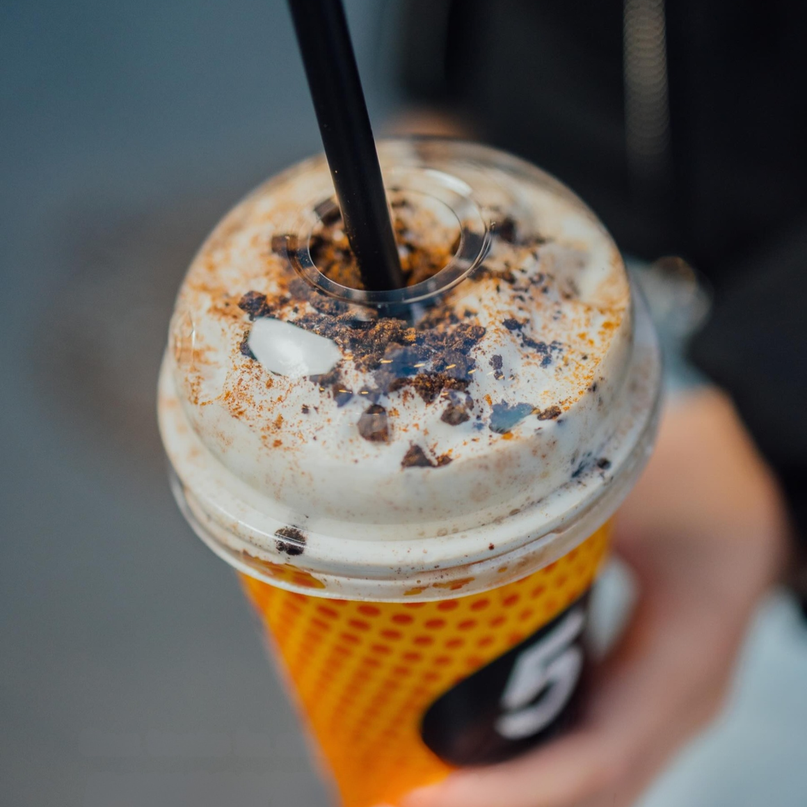 Latte rece cu frișcă și topping de scorțișoară și ciocolată, servit la pachet de 5 to go, o opțiune de sezon pentru iubitorii de cafea.