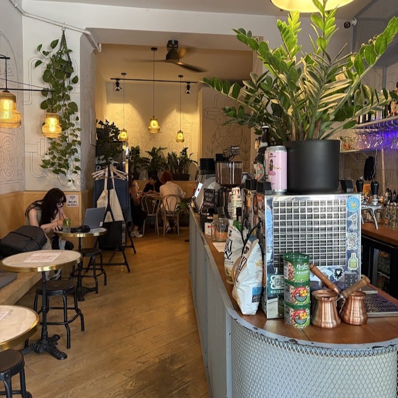 Uzina Coffee, cafenea din București, cu interior decorat cu plante, corpuri de iluminat calde și zonă de bar pentru cafea de specialitate.